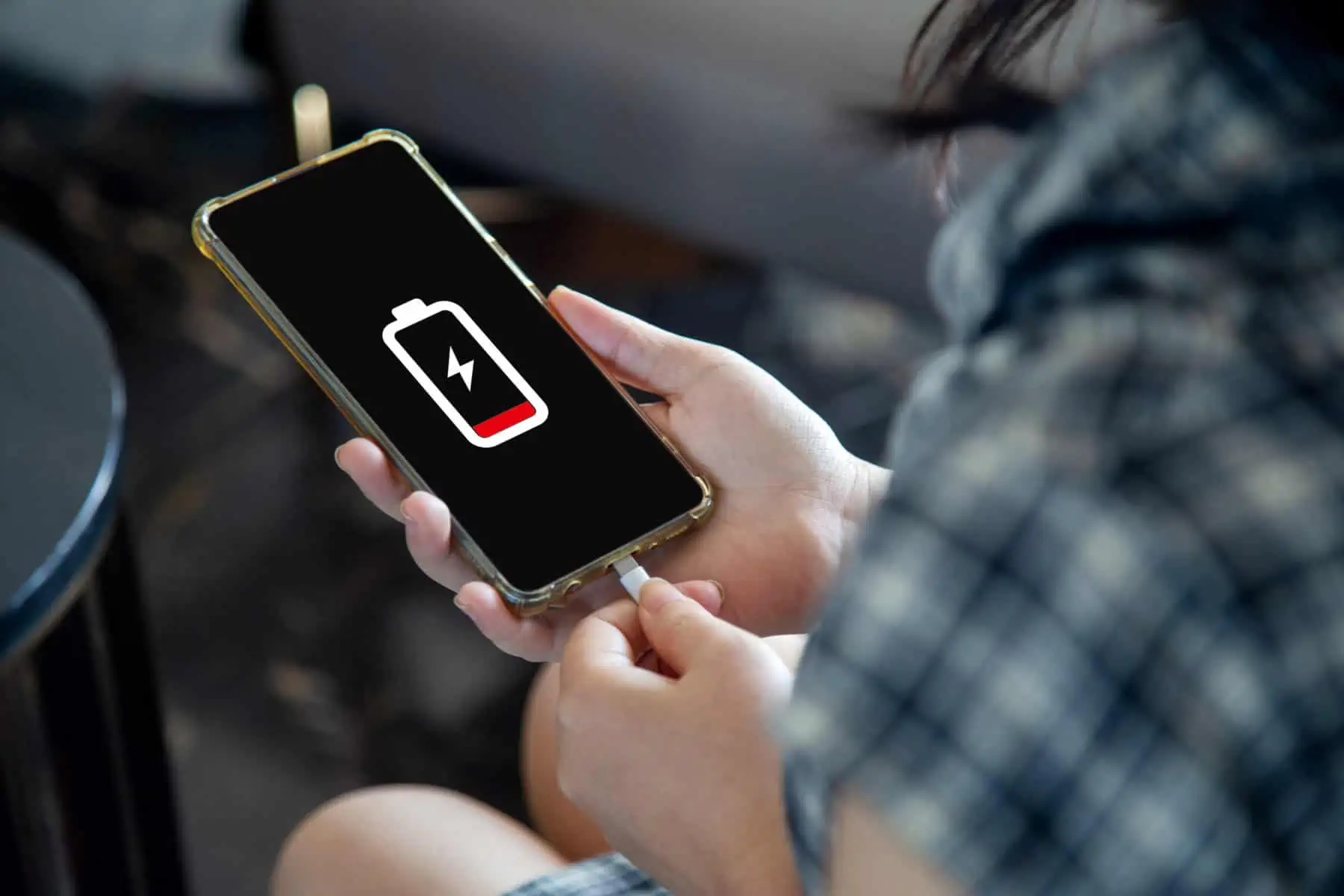 Cierre una mujer con las manos cargando su teléfono móvil con la carga I Los mitos sobre la batería del teléfono inteligente, la batería dan por menos tiempo, la batería puede manejar más tiempo, Android para la batería dura la batería.