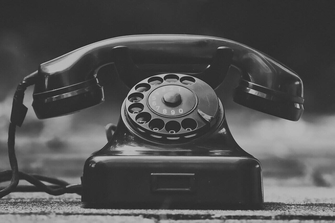 Teléfono fijo antiguo de hierro en blanco y negro, símbolo de la comunicación clásica.