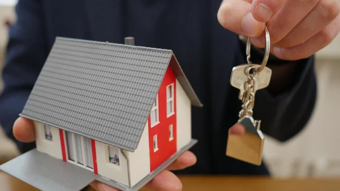Casa en miniatura en mano con llaves.